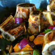 Load image into Gallery viewer, 100% grass-fed and field harvested bison soup bones on a sheet tray with roasted vegetables