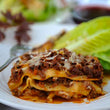 Load image into Gallery viewer, A plate of cooked lasagna with a layer of ground buffalo meat on top, served with a side salad.