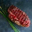 Load image into Gallery viewer, 100% grass fed and field harvested raw bison chuck roast in a net on a black background
