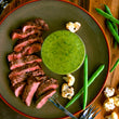 Load image into Gallery viewer, 100% grass fed and field harvested buffalo flat iron steak on a plate with green bagna cauda sauce