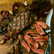 Load image into Gallery viewer, Grilled steak with sliced pieces on a wooden cutting board, accompanied by mushrooms and a glass of red wine.