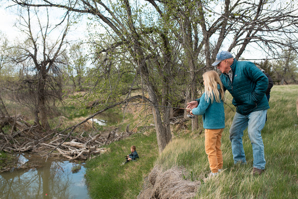 Wild Idea founder Dan O'Brien teaching young girl to fish by a creek on Cheyenne River Buffalo Ranch