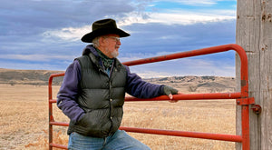 gervase standing at a red gate on the prairie