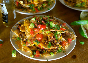 Bison Nachos with tomatoes, onion & avocado on a plate
