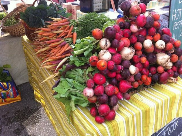 Yellow table piled with radishes and carrots
