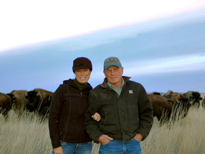 Dan and Jill in front of buffalo herd wearing coats and hats