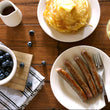 Load image into Gallery viewer, 100% grass fed and field harvested bison breakfast sausage links on a wooden table with pancakes, blueberries, and syrup.
