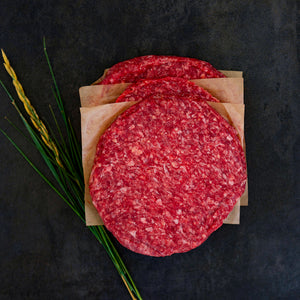 100% grass-fed and field harvested raw buffalo burger patties on a black background