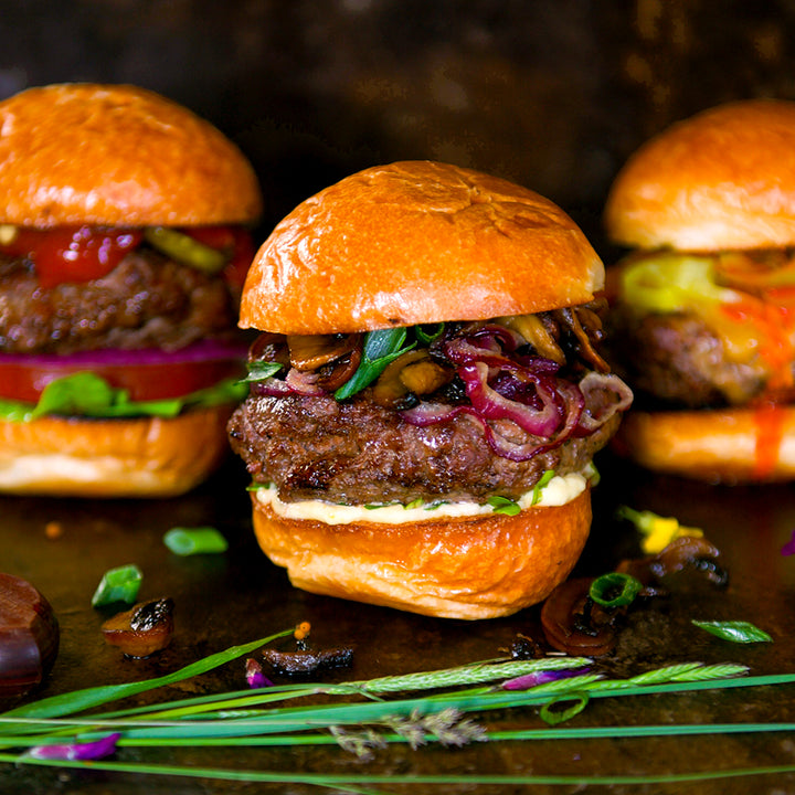 100% grass-fed and field harvested buffalo burger with grilled onions, green onions, and soft cheese on a brioche bun