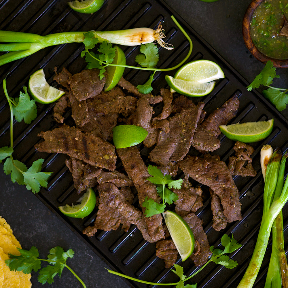 Carne asada on a skillet with lime and cilantro
