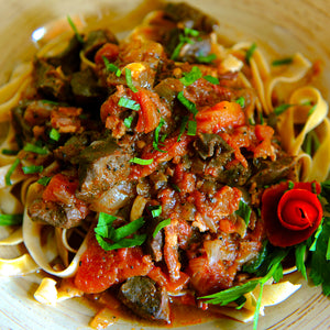 100% grass-fed and field harvested bison heart with stewed tomatoes on top of egg noodles