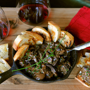 100% grass-fed and field harvested buffalo kidney in a black skillet with crostini and red wine