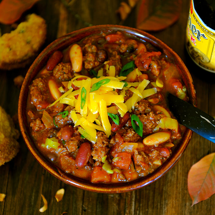 100% grass-fed and field harvested ground buffalo chili with cheese on top on a wooden table