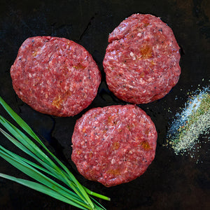 100% grass-fed and field harvested ground buffalo burgers on a black background with seasonings