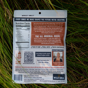 Back of a Wild Idea jerky package placed on green grass, showing nutrition facts, branding, and product details.