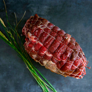 100% grass fed and field harvested raw bison chuck roast in a net on a black background