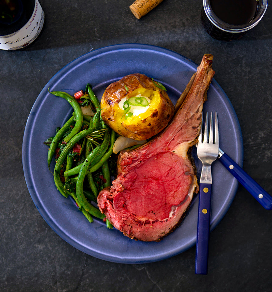 100% grass-fed and field harvested bison prime rib roast plated with green beans and a baked potato