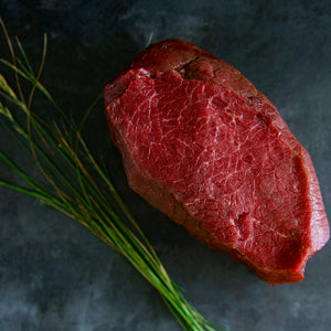 100% grass-fed and field harvested bison sirloin tip roast on a black background