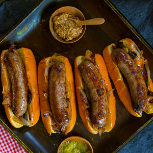 100% grass-fed and field harvested bison bratwurst in buns on a tray with mustard