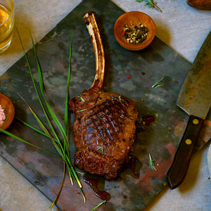 100% grass-fed and field harvested buffalo bone-in ribeye on a black cutting board with grill marks