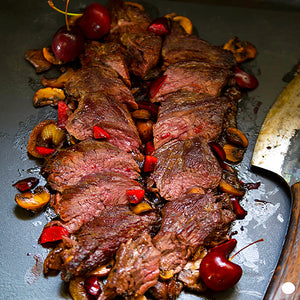 100% grass-fed and field harvested grilled bison hanger steak on a grill with cherries