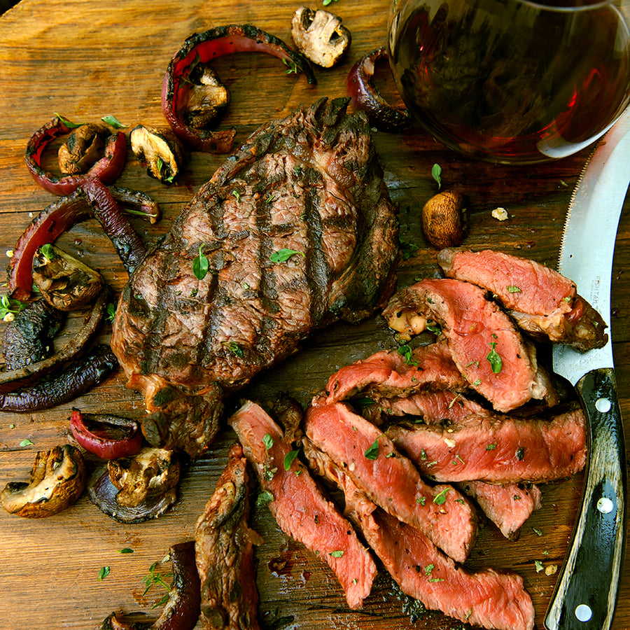 100% grass-fed and field harvested grilled bison ribeye with grilled onions a cutting board