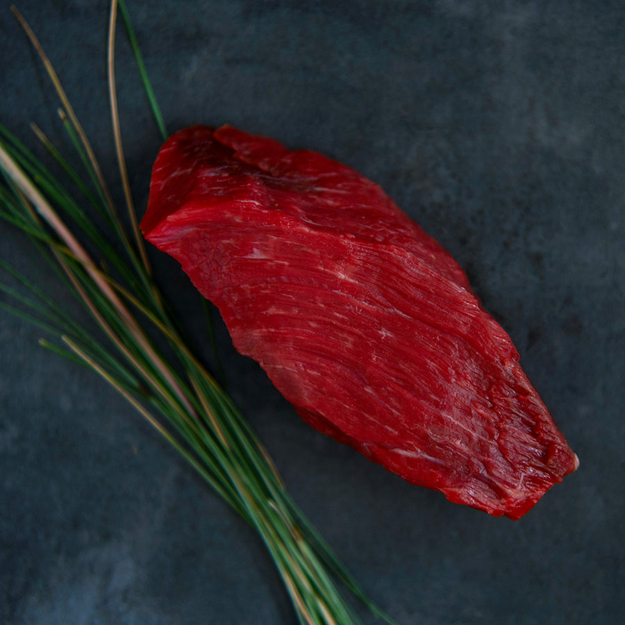 100% grass-fed and field harvested raw bison sirloin steak on a black background