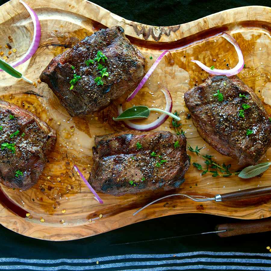 100% grass-fed and field harvested grilled bison sirloin steaks on a wooden cutting board