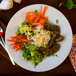 100% grass-fed and field harvested bison steak strips with rice noodles on a white bowl