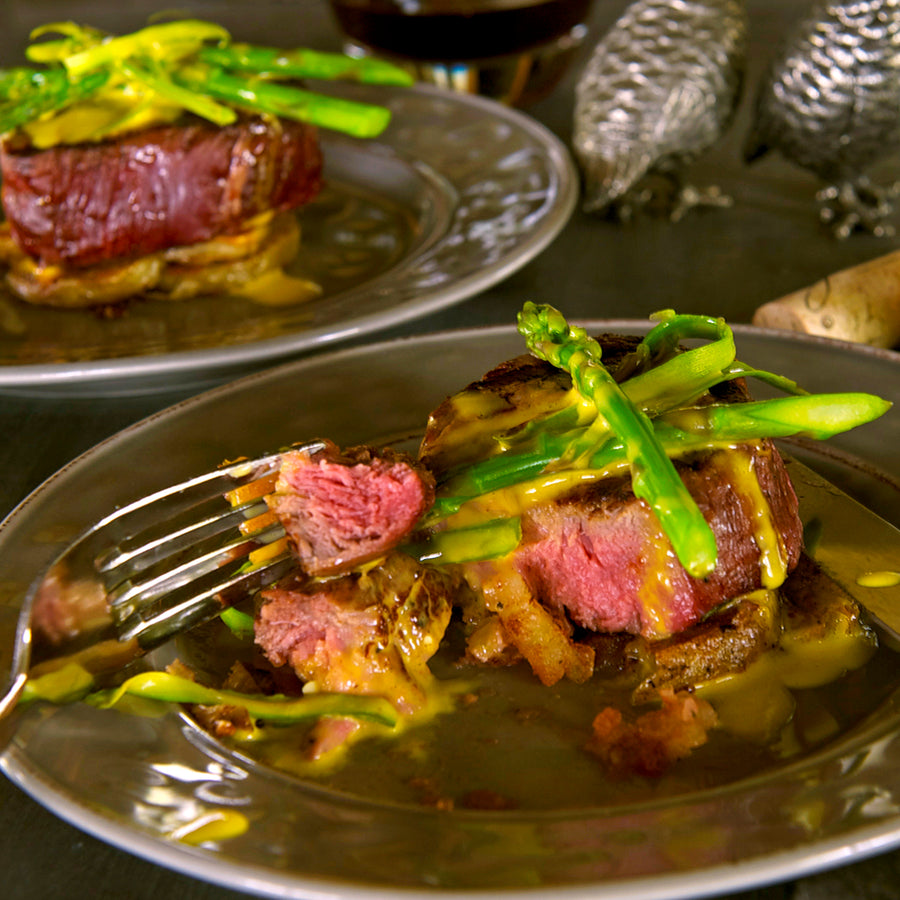 100% grass-fed and field harvested grilled bison tenderloin with asparagus on a plate with a fork 