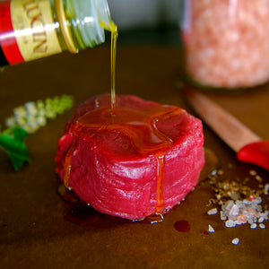 100% grass fed and field harvested raw bison filet with olive oil on a plain table