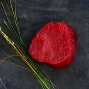 100% grass fed and field harvested raw bison tenderloin filet on a black background