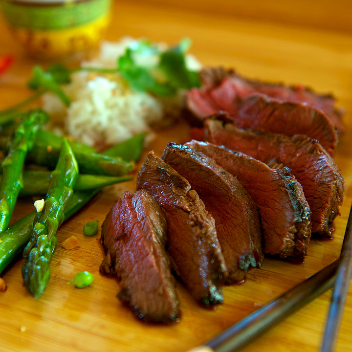 100% grass-fed and field harvested bison sirloin steak sliced with asparagus