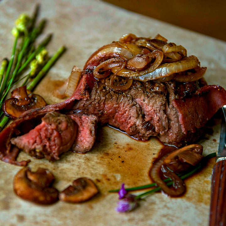 100% grass-fed and field harvested bison top sirloin steak with grilled onions and bacon