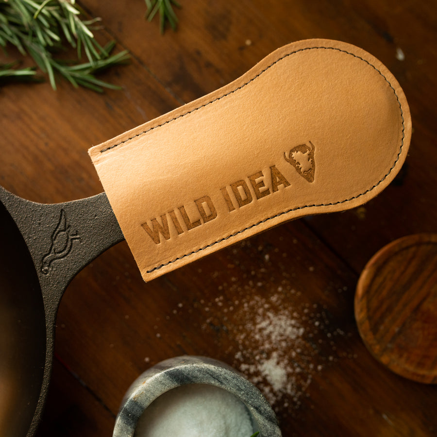 Leather skillet handle on cast iron pan with brand reading "Wild Idea"