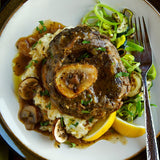 overhead shot of buffalo osso bucco atop a bed of risotto and greens